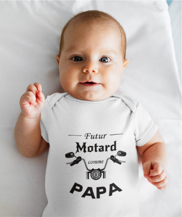 Sur cette image on peut voir un body personnalisé "Futur motard comme papa" avec le guidon d'une moto. Il est imprimé au sein de notre boutique l'usine du t-shirt à Caissargues dans le Gard.