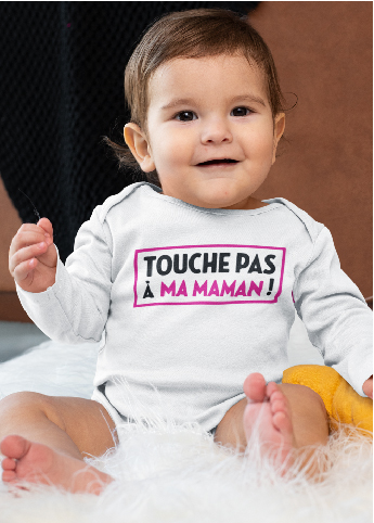 Sur cette image on peut voir un body personnalisé "Touche pas à ma maman". il est porté par un bébé brun aux yeux marron. Ce body est personnalisé à Caissargues dans le Gard.